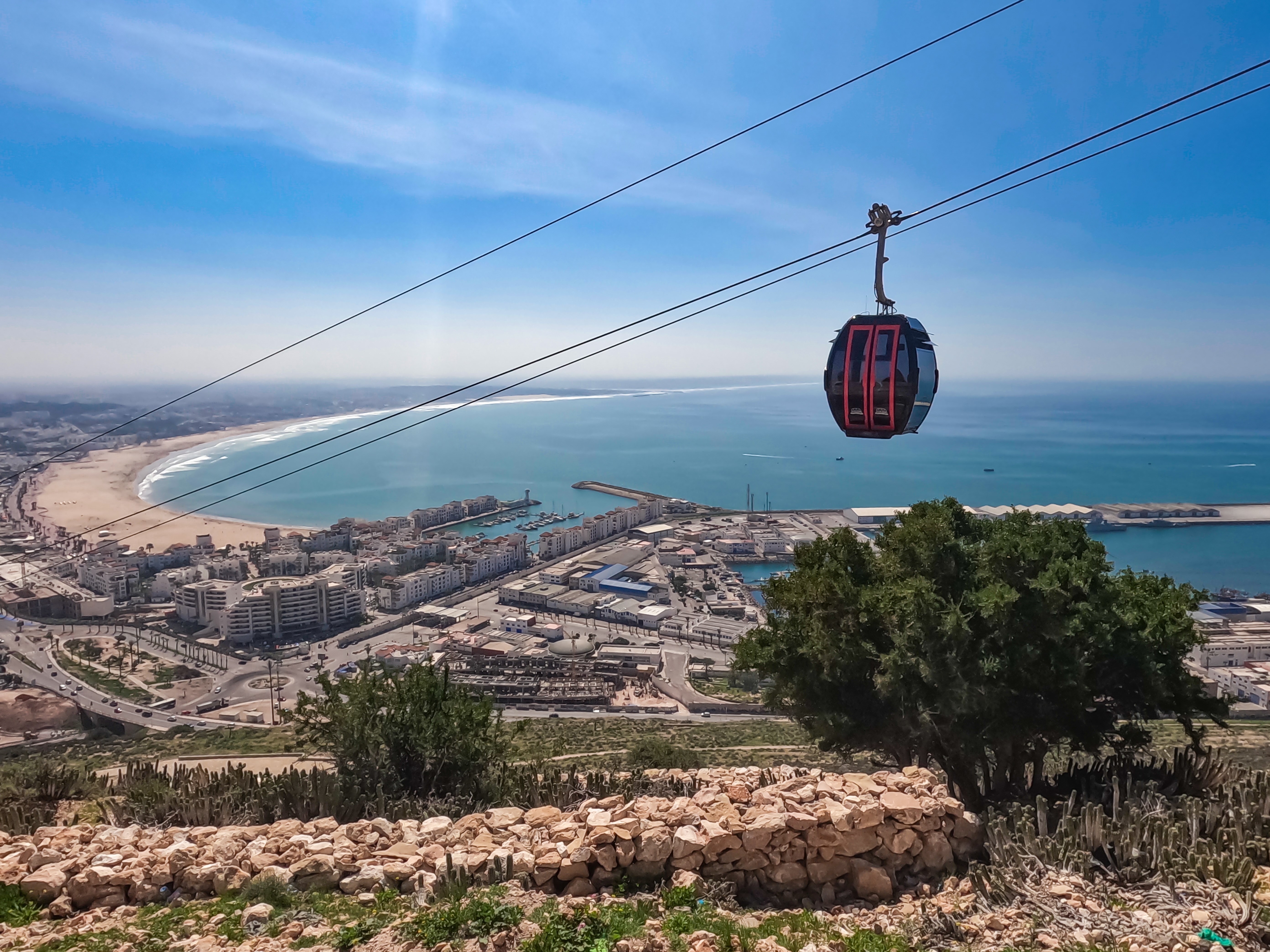 Midway view from Agadir Oufla climb, capturing Agadir's cityscape, Atlantic beach and cable cars