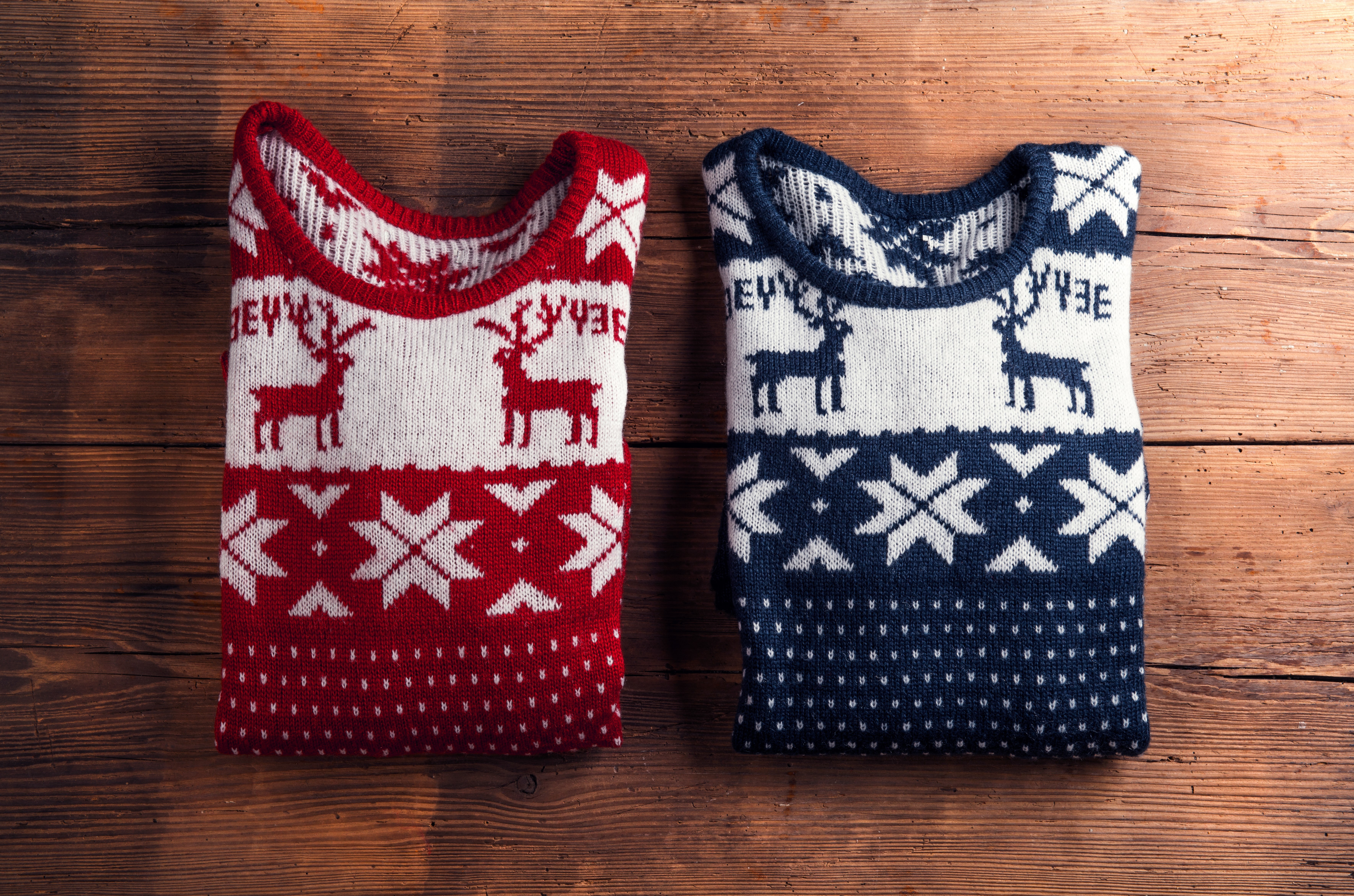 Two winter sweaters laid on a wooden table background