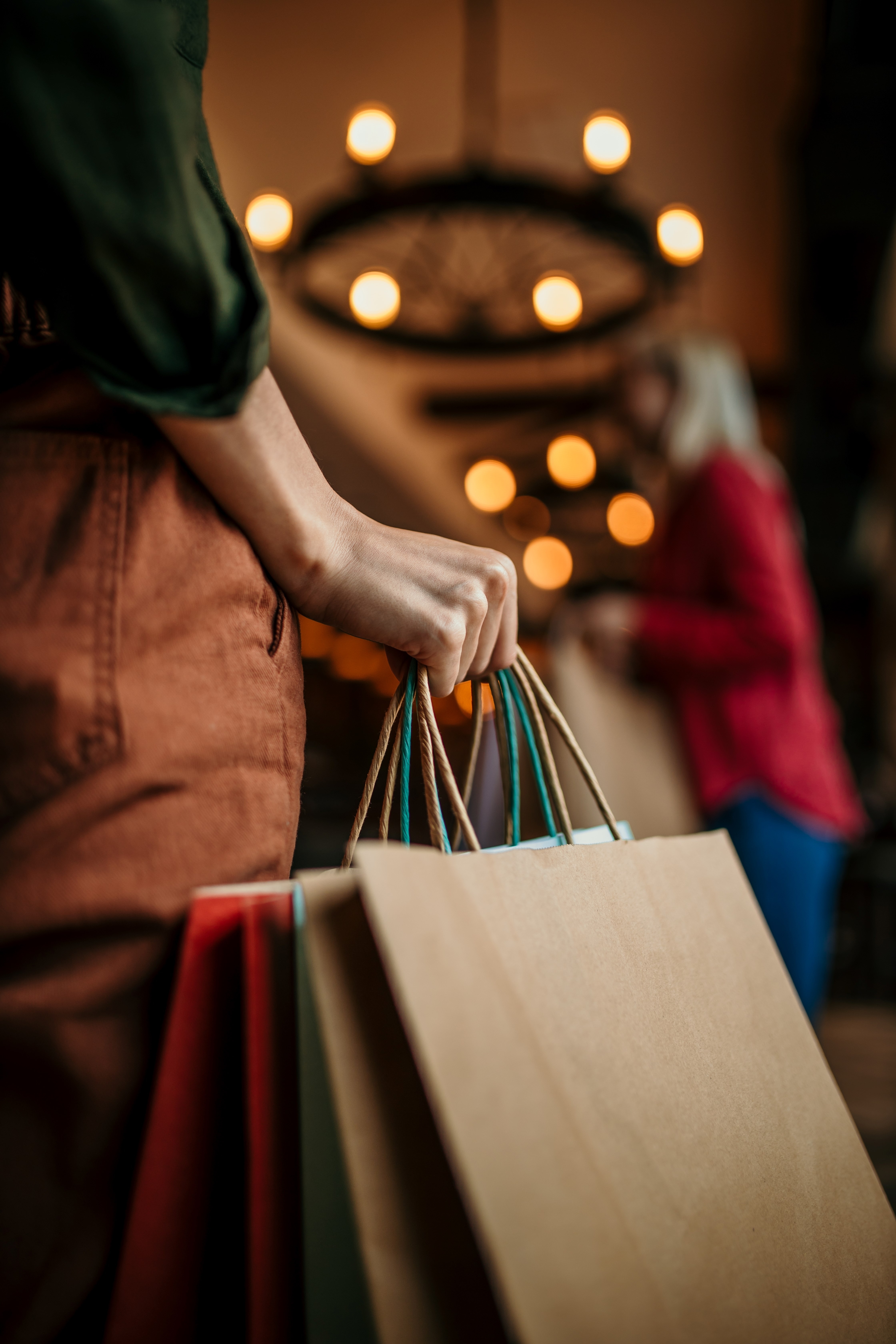 An unrecognizable female hand holding a bunch of shopping bags indoors