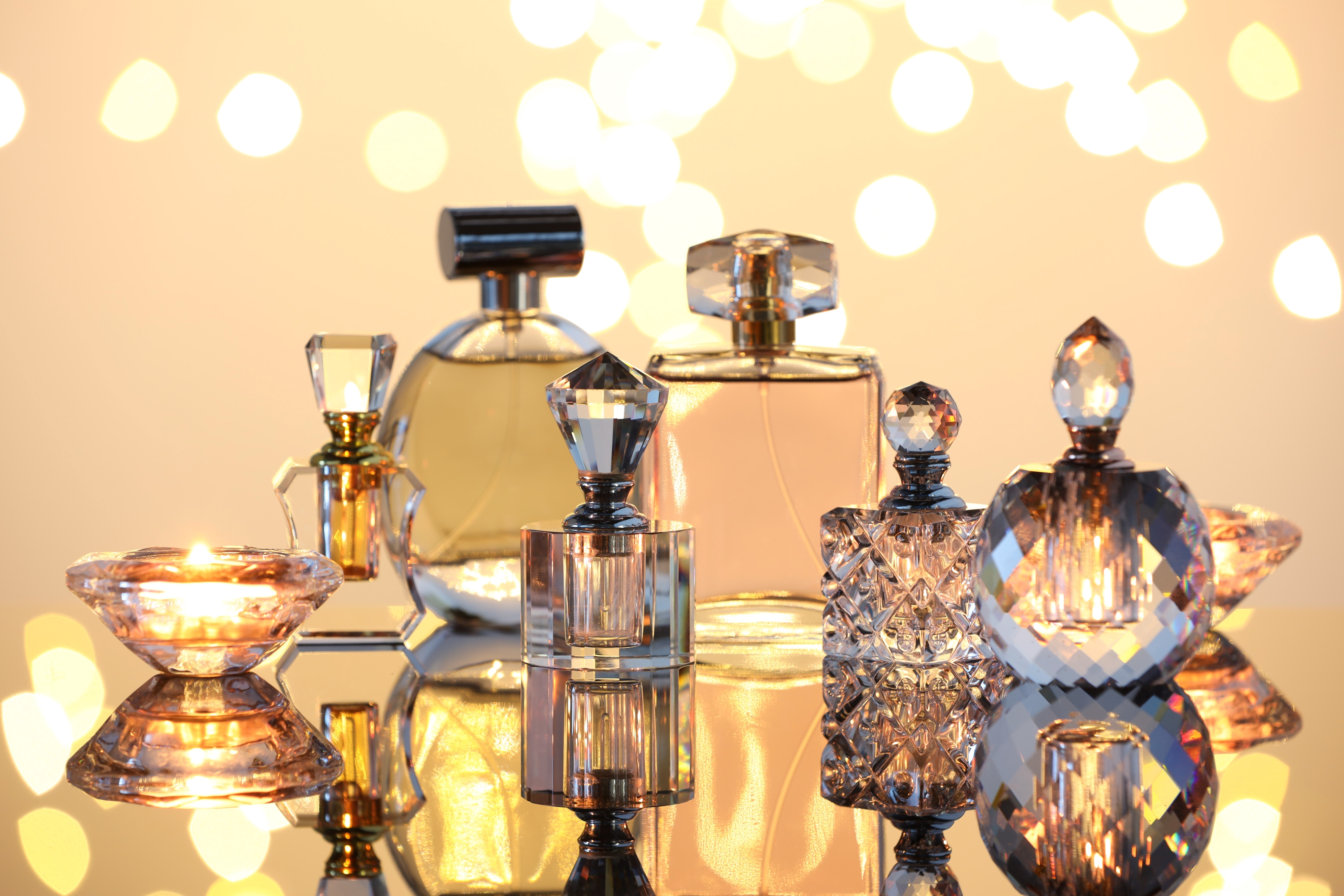 Different luxury perfumes on glass surface. Bokeh effect