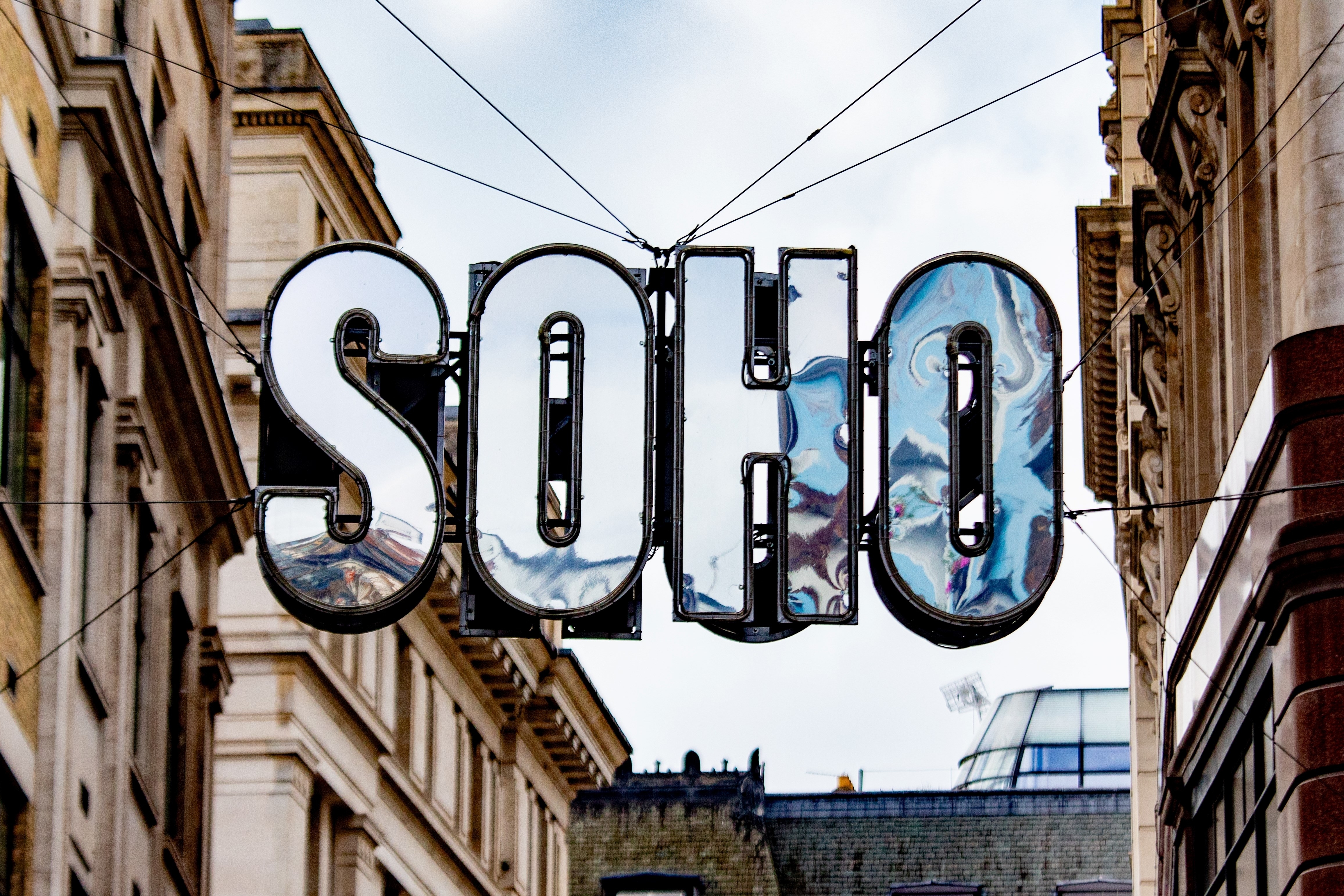 A close-up of the iconic Soho sign amidst historic buildings in London.