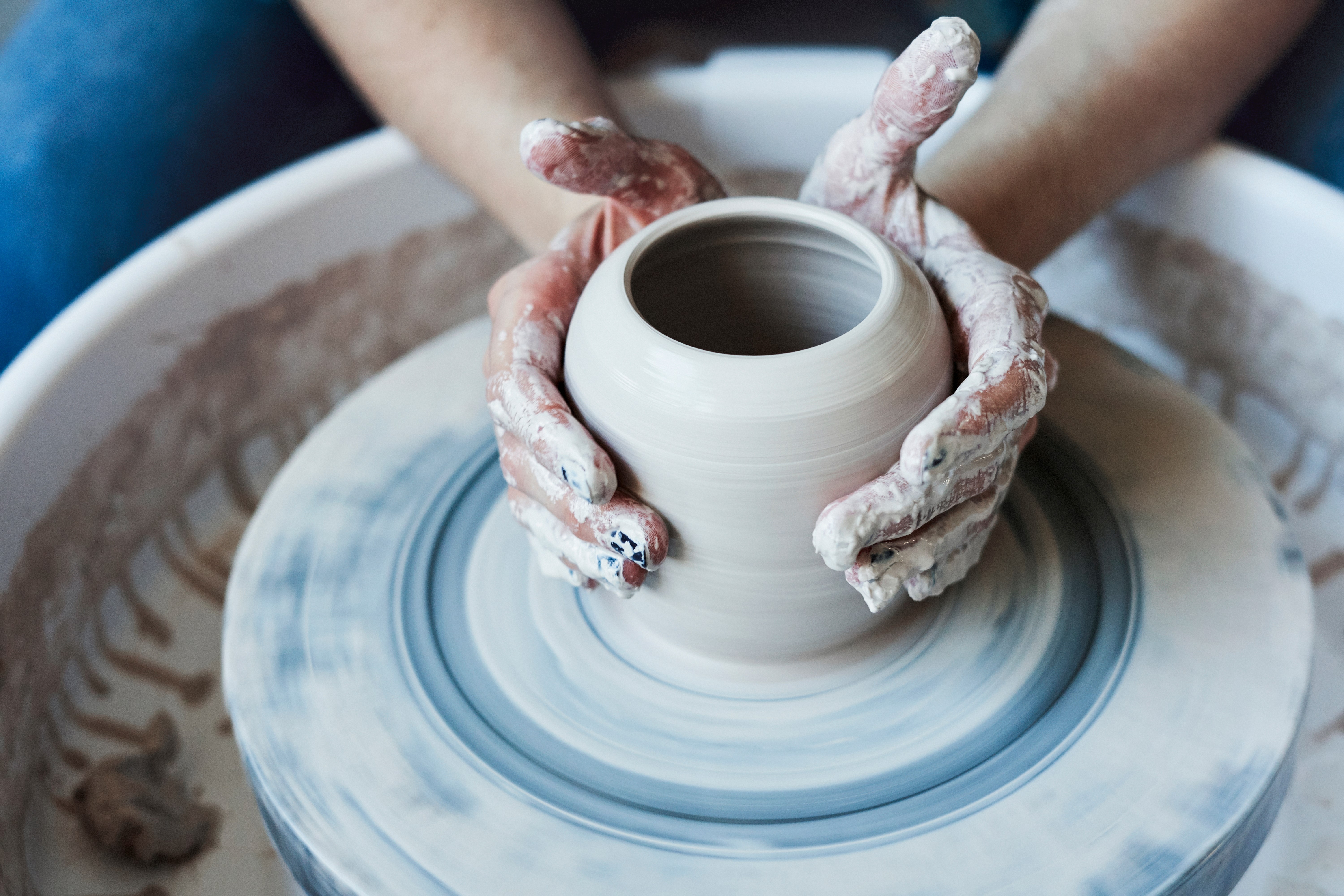 Hands crafting a vase in a ceramics studio