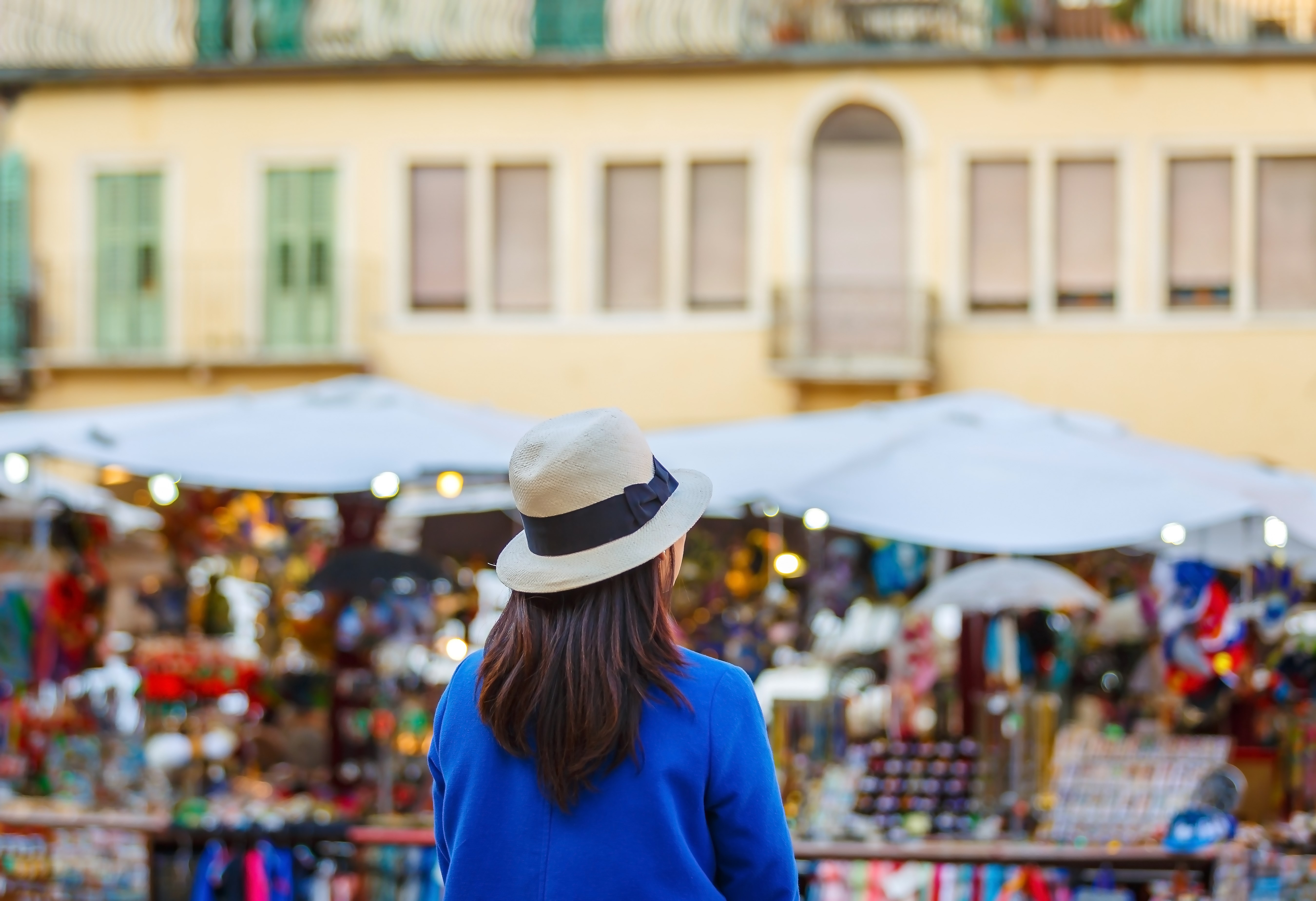 Back of female traveler looking at local European market in Italy