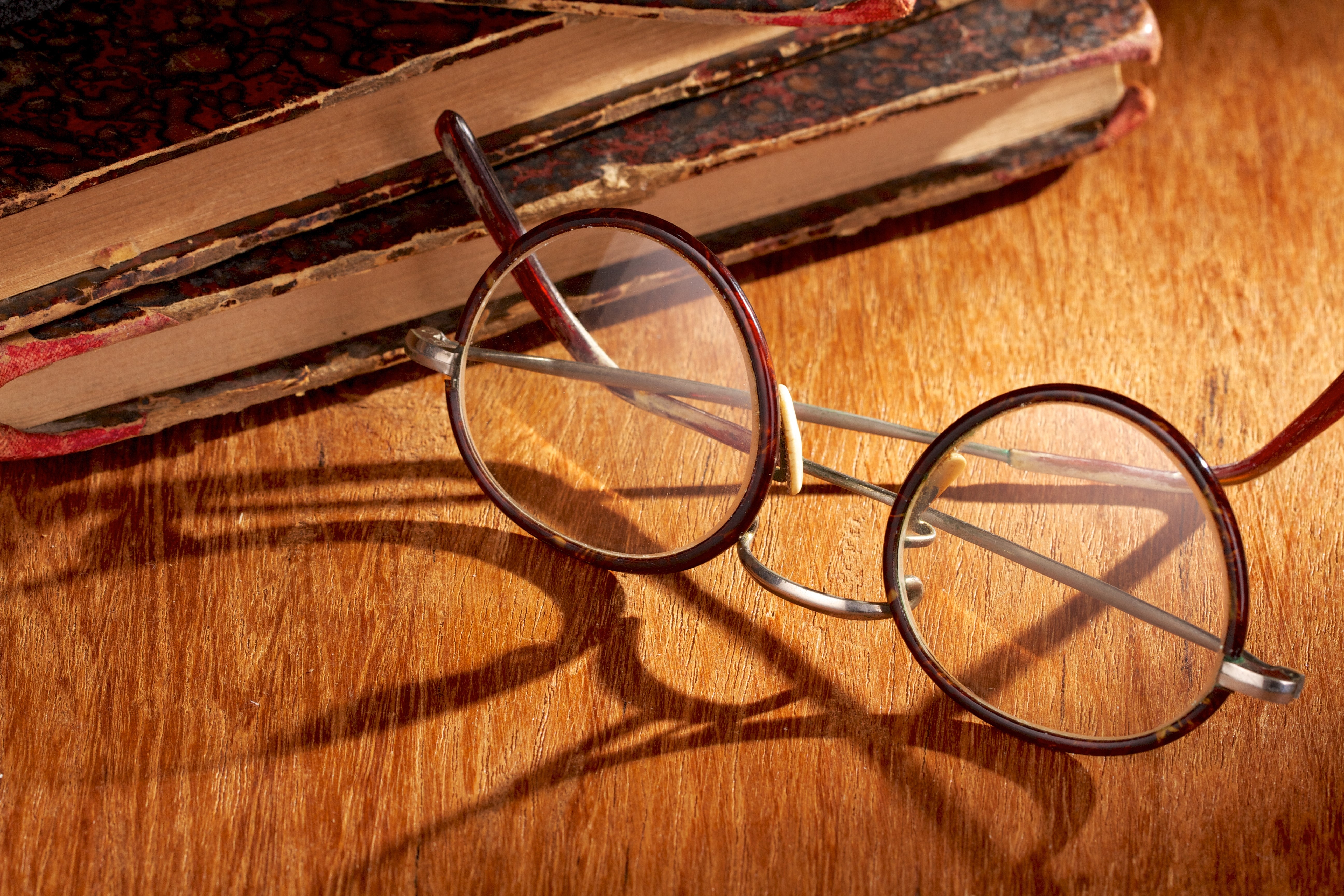 Long shadow from vintage eyewear over a wooden table