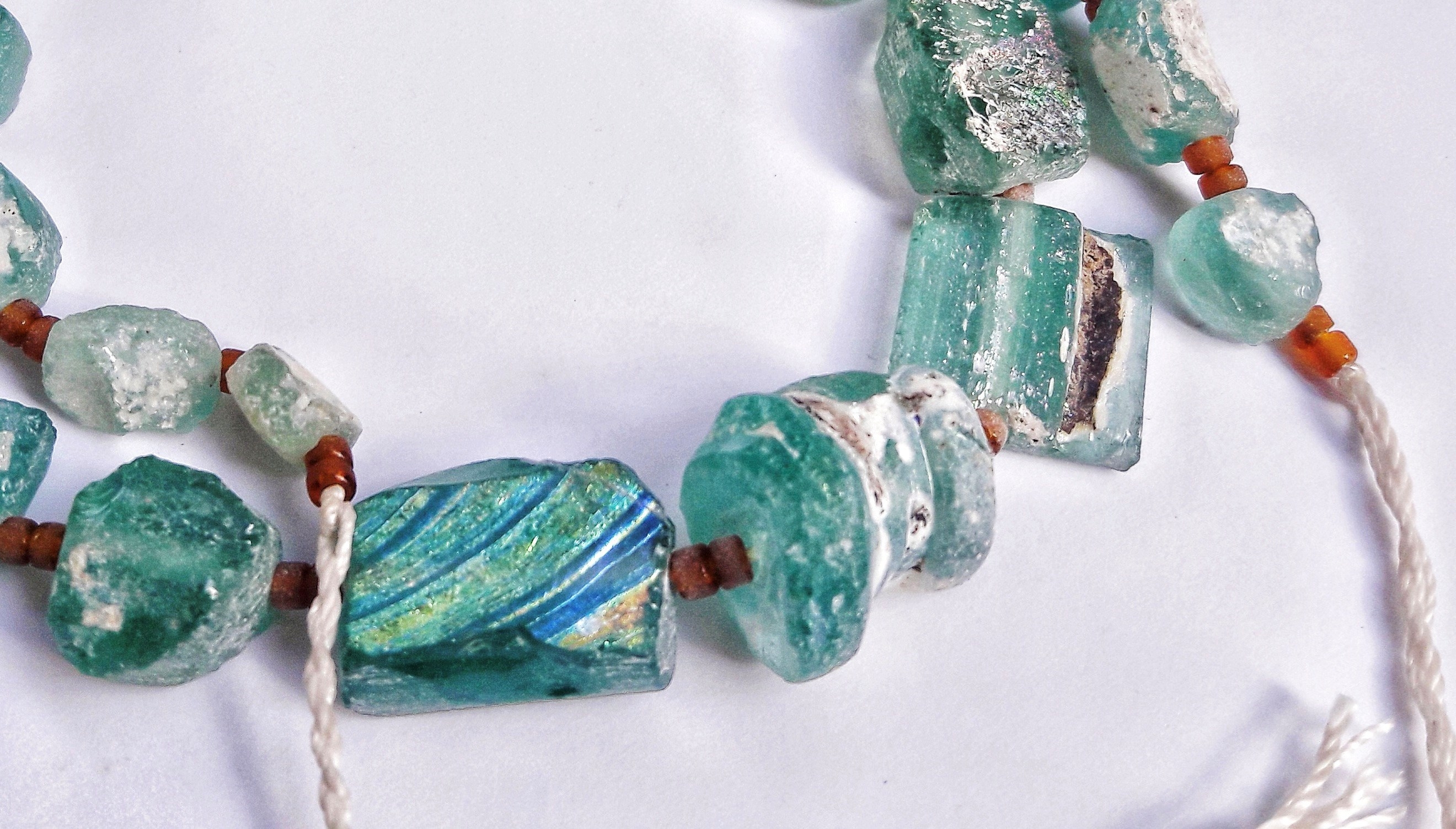 A String of Ancient Blue Roman Glass Beads on White Background