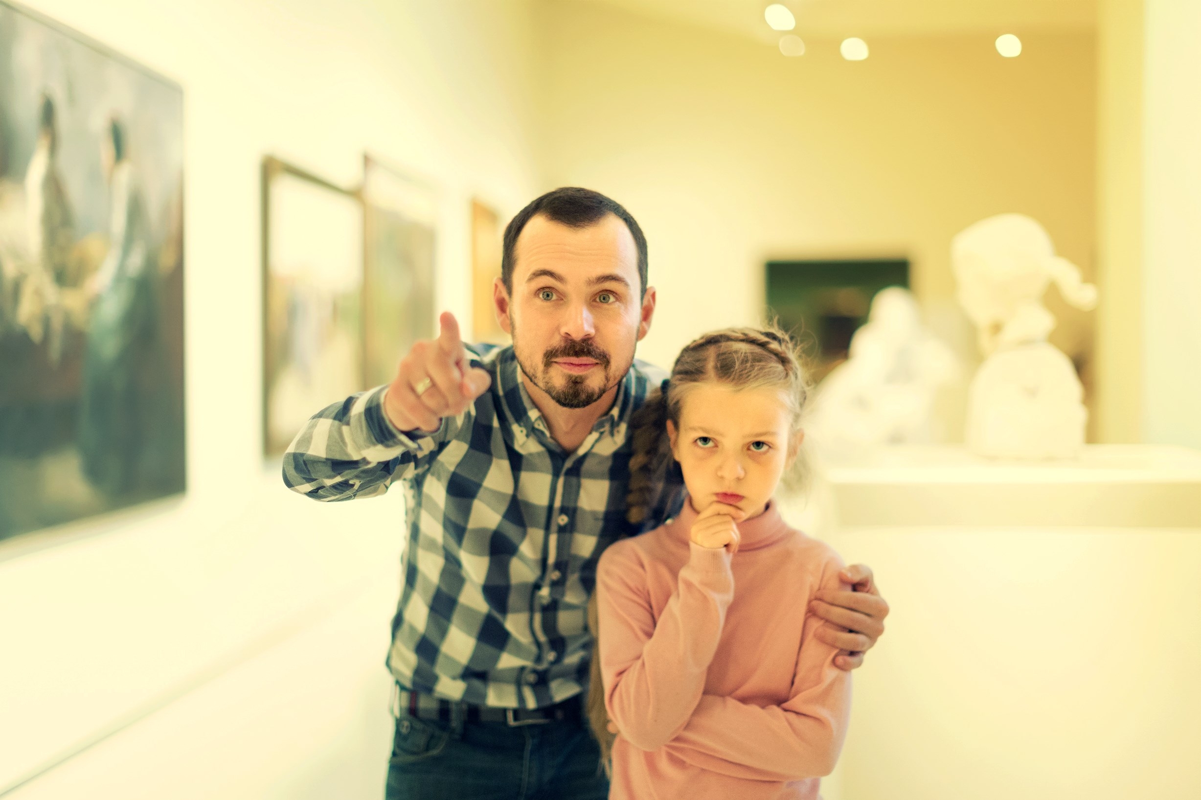 Father and daughter regarding paintings in halls of museum