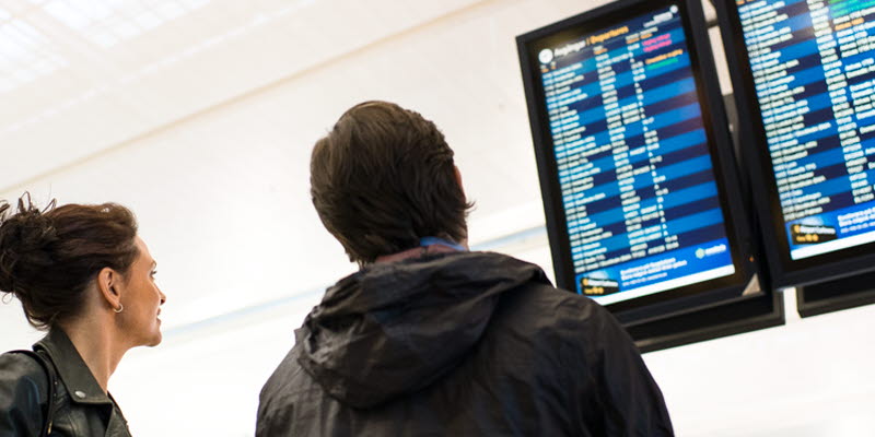 Two people looking at departure signs Two people looking at departure signs