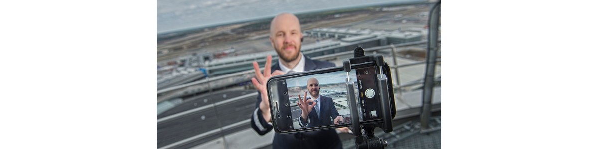 A man in front of a camera lens and Arlanda airport in the background A man in front of a camera lens and Arlanda airport in the background
