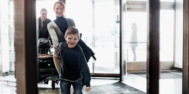 A happy family entering the airport Boy holding woman's hand at the entry of a terminal at Stockholm Arlanda