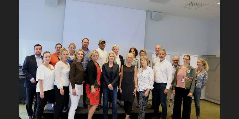 Twenty people standing in front of a white wall Twenty people standing in front of a white wall