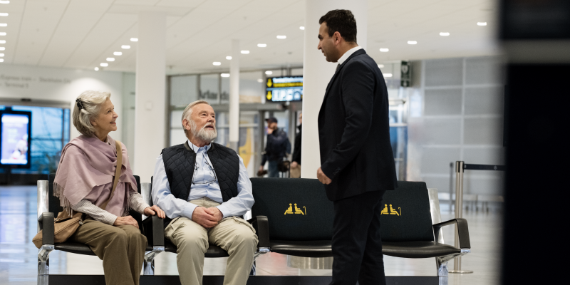 An elderly couple sitting and a man standing An elderly couple sitting and a man standing