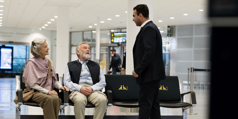 An elderly couple sitting and a man standing An elderly couple sitting and a man standing