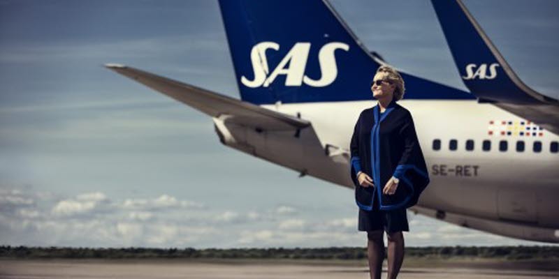 An SAS employee in front of a SAS plane on the runway An SAS employee in front of a SAS plane on the runway