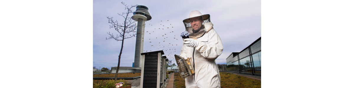 A man in a bee suit with Arlanda flight tower in the background A man in a bee suit with Arlanda flight tower in the background