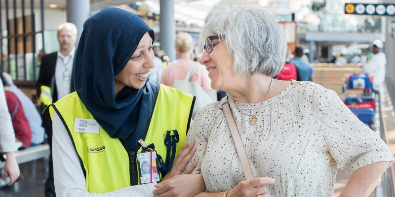 Two women standing in a terminal looking at each other Two women standing in a terminal looking at each other