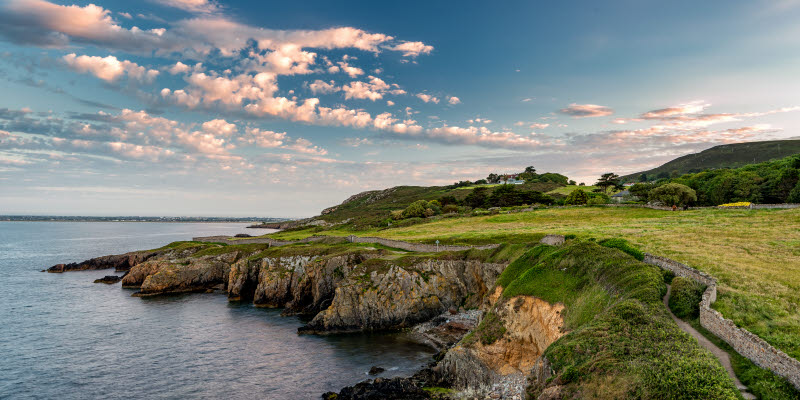 Irish landscape with green cliffs near water and blue sky Irish landscape with green cliffs near water and blue sky