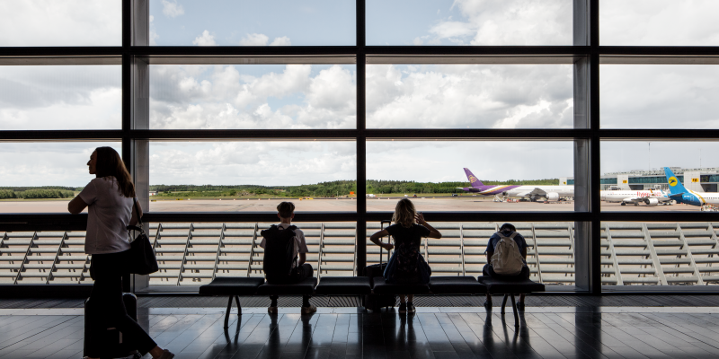People at a window in SkyCity Arlanda overlooking aeroplanes at the runway People at a window in SkyCity Arlanda overlooking aeroplanes at the runway