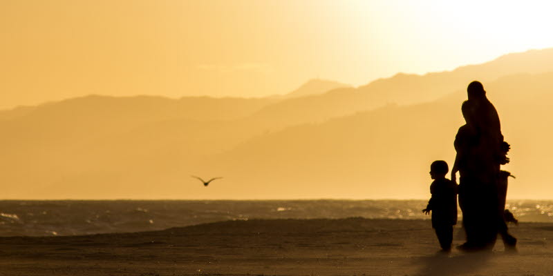 People walking at the beach in the sunset People walking at the beach in the sunset