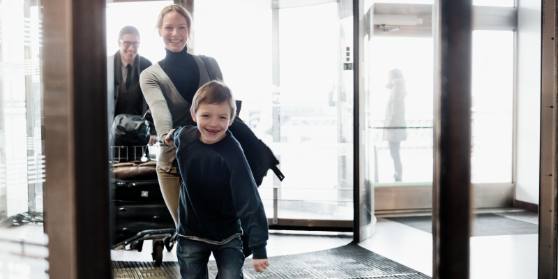 A happy family entering the airport Boy holding woman's hand at the entry of a terminal at Stockholm Arlanda