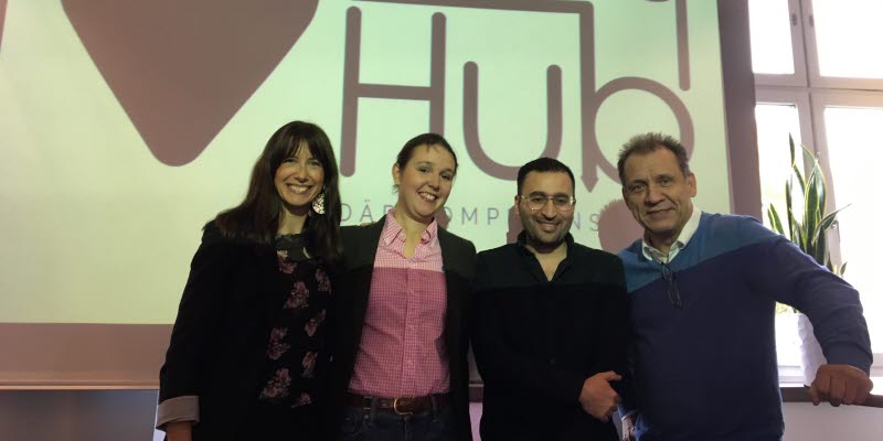 Four people standning in front of a sign saying Entry Hub Four people standning in front of a sign saying Entry Hub